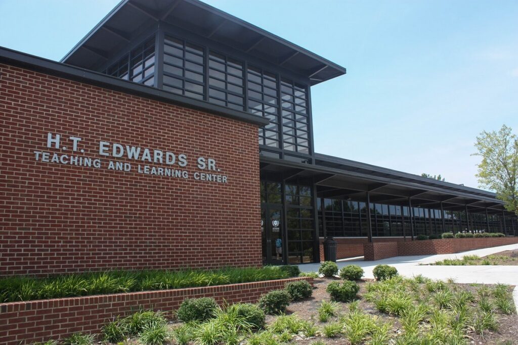 Exterior of the H.T. Edwards Sr. Teaching and Learning Center, a modern brick building with large windows, surrounded by landscaped bushes and a clear blue sky.