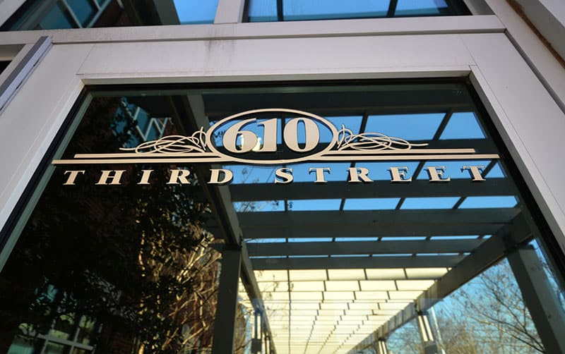 A glass door displays the address 610 Third Street in bold, decorative letters, with reflections of trees and a metal awning visible in the glass.